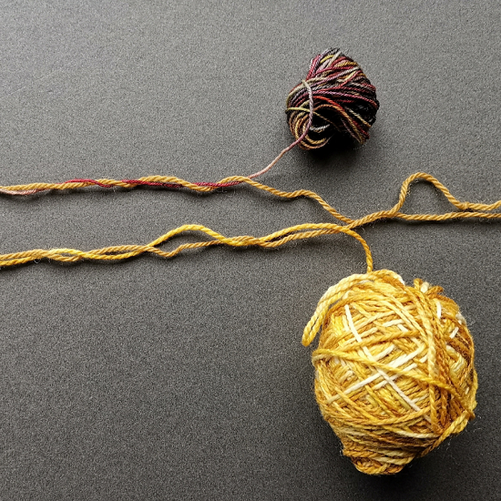 Trial blends to make a new yarn from two strands.  Both use a dirty mustard solid colour and the first tries is twisted with a yellow and mustard yarn.  The second is the solid mustard with a variegated yarn which has a lot of wien red in it.