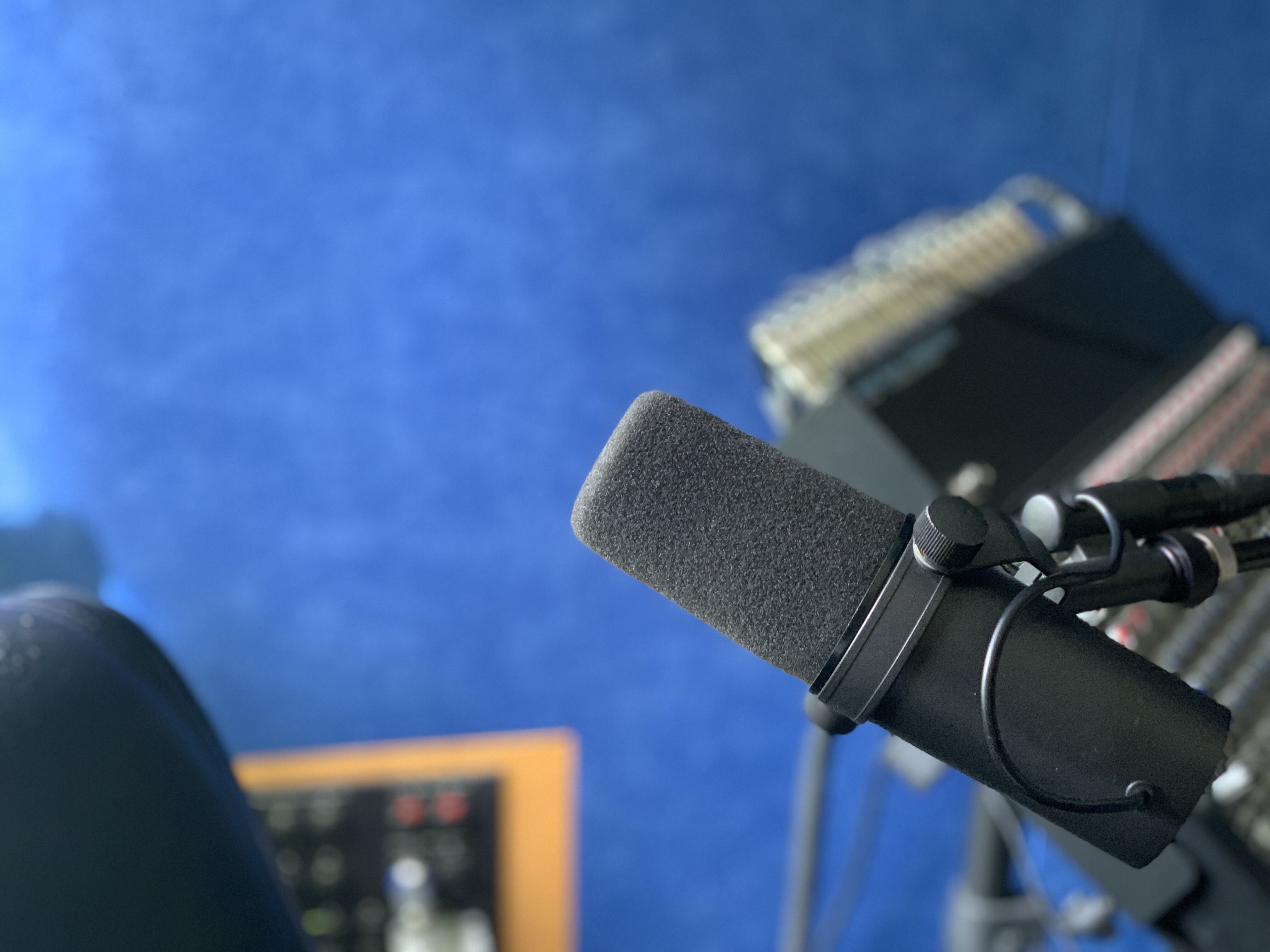 The microphone in Steven Leavitt's studio with blue background and mixing board