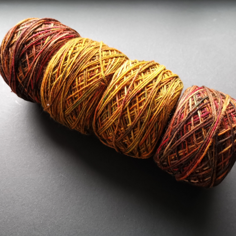 Set of 4 cakes of variegated yarn in a fade.  Two outer cakes are the same rusty red colour.  The two inner colours are a brighter rusty orange and mustard colour.