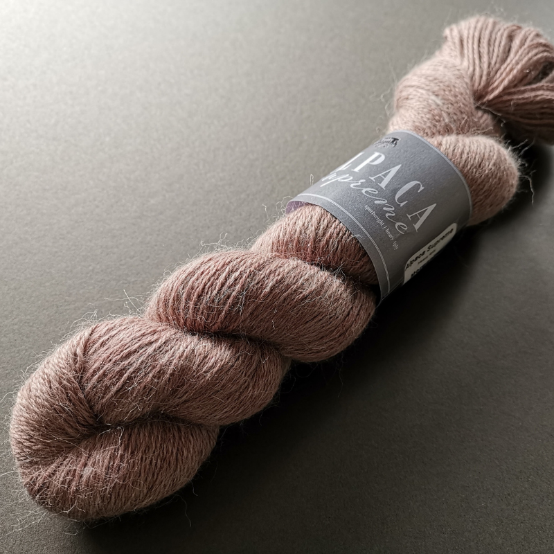 Skein of Alpaca Supreme on a grey background.  The skein is soft and a light vintage pink.