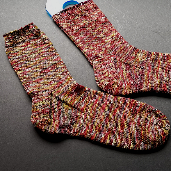 Pair of knitted socks in a variegated yarn that has all of the Autumnal colours in one!